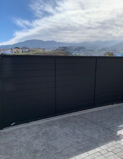 Cancela corredera de gran formato con sistema de guía y lamas horizontales