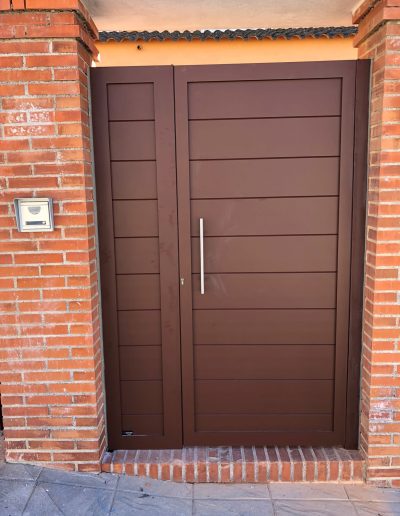 Puerta de entrada principal color chocolate con panel fijo lateral
