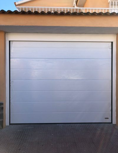 Puerta de garaje seccional blanca con paneles acanalados horizontales