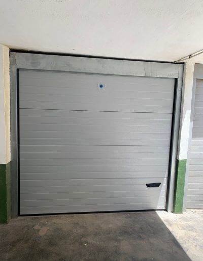 Puerta seccional de garaje en color gris plata con tirador integrado